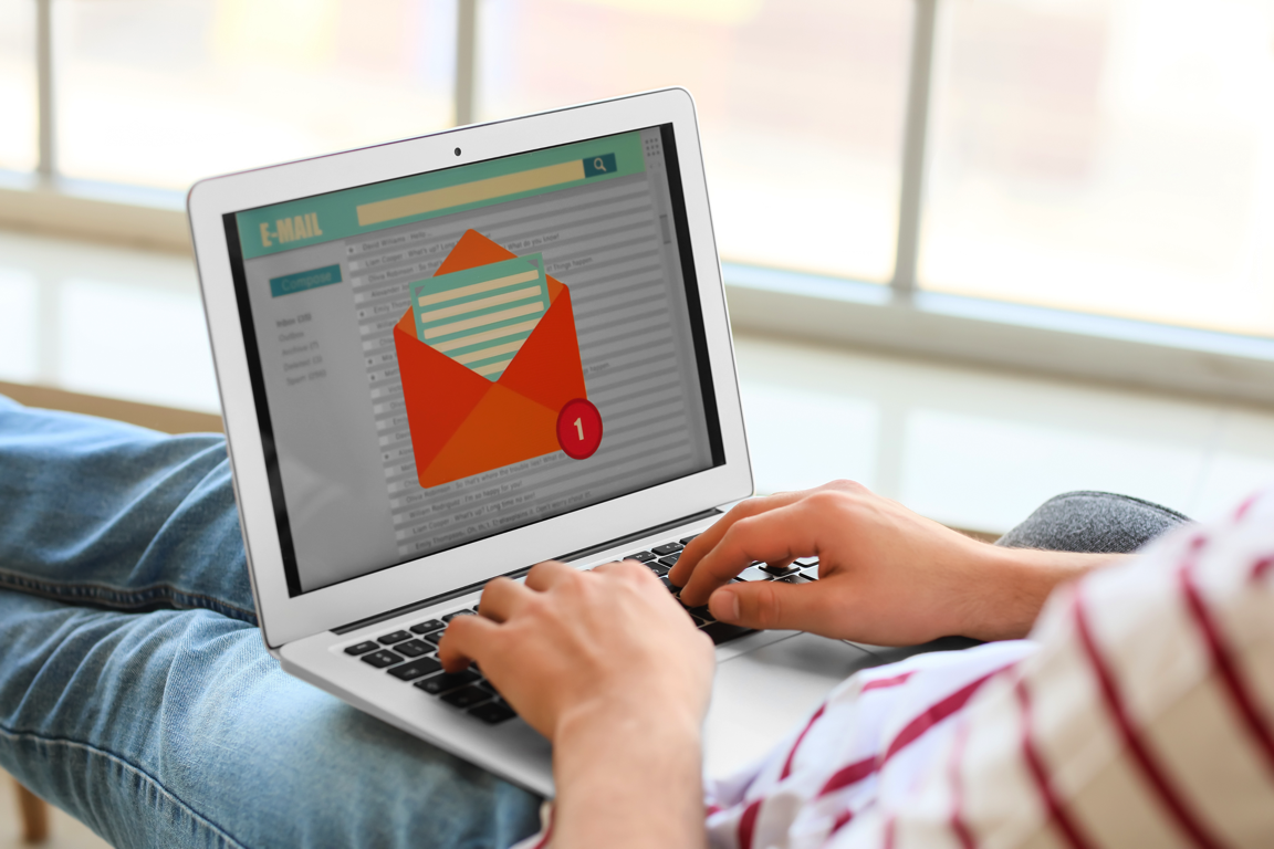 person sitting down with a laptop. On the screen a new email icon can be seen